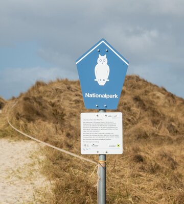 Nationalpark-Schild vor Dünen