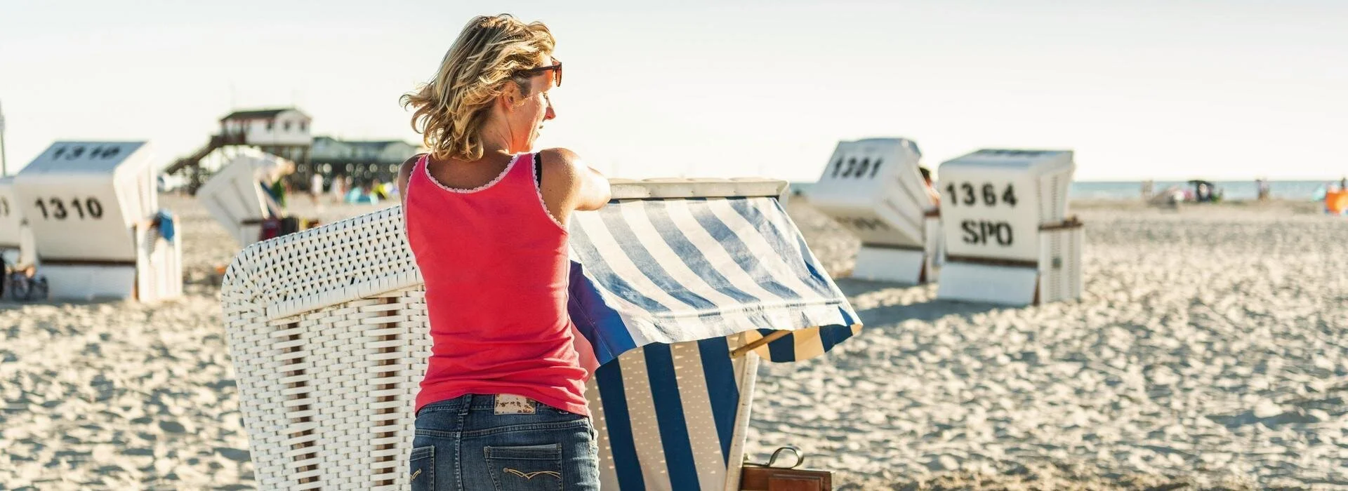Frau lehnt sich an einen Strandkorb am Strandabschnitt Ording