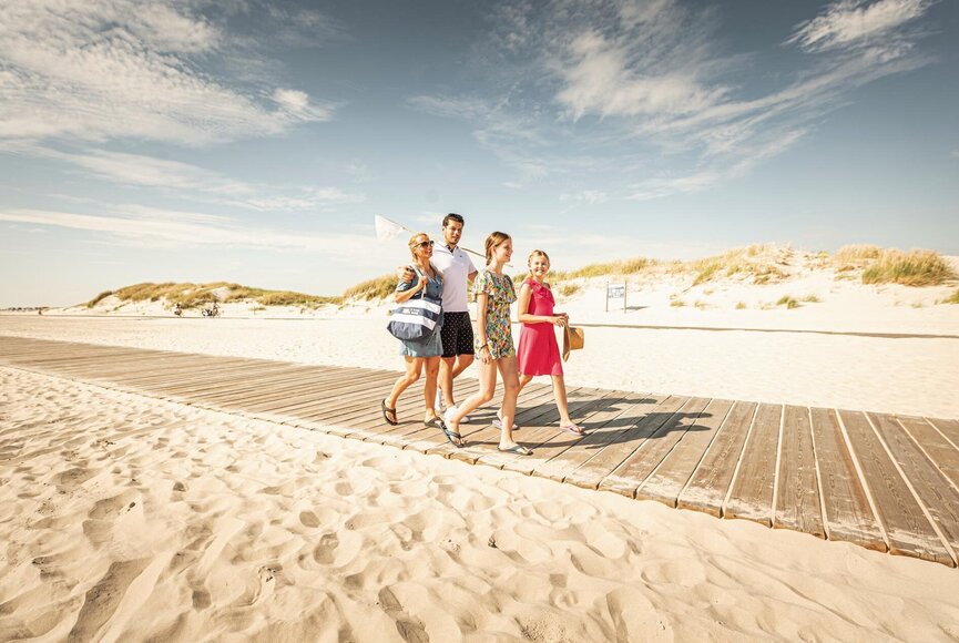 Familie läuft über den Steg zum Strand
