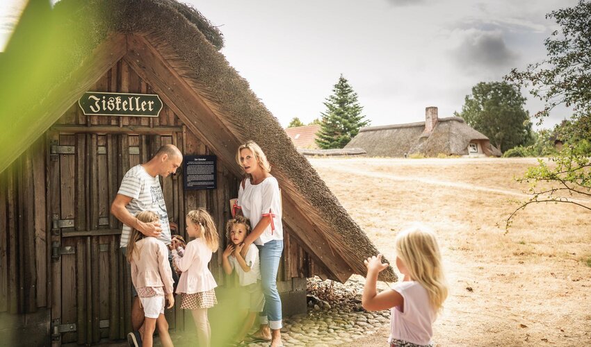 Familie vor dem Nachbau eines Eiskellers bei der historischen Insel