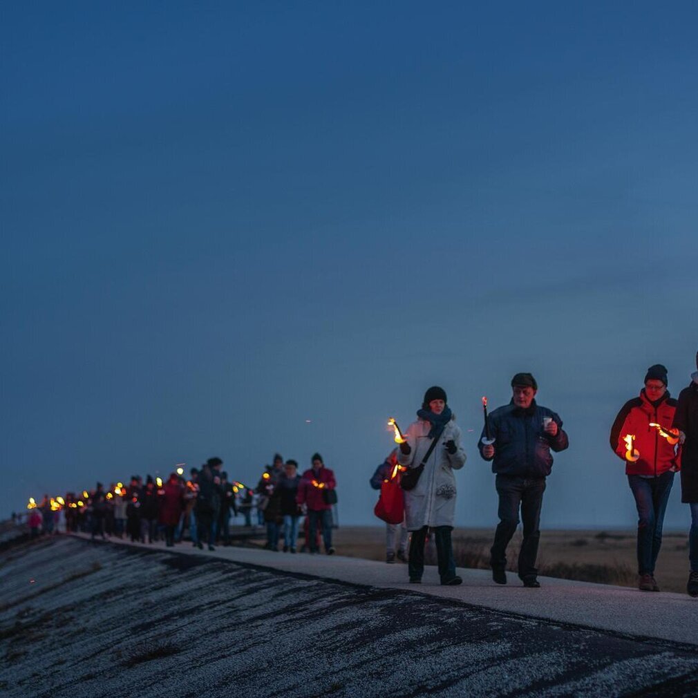 Menschen mit Fackeln auf dem Deich