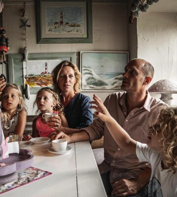Eltern mit drei Kindern an einem Holztisch in einem urigen Café