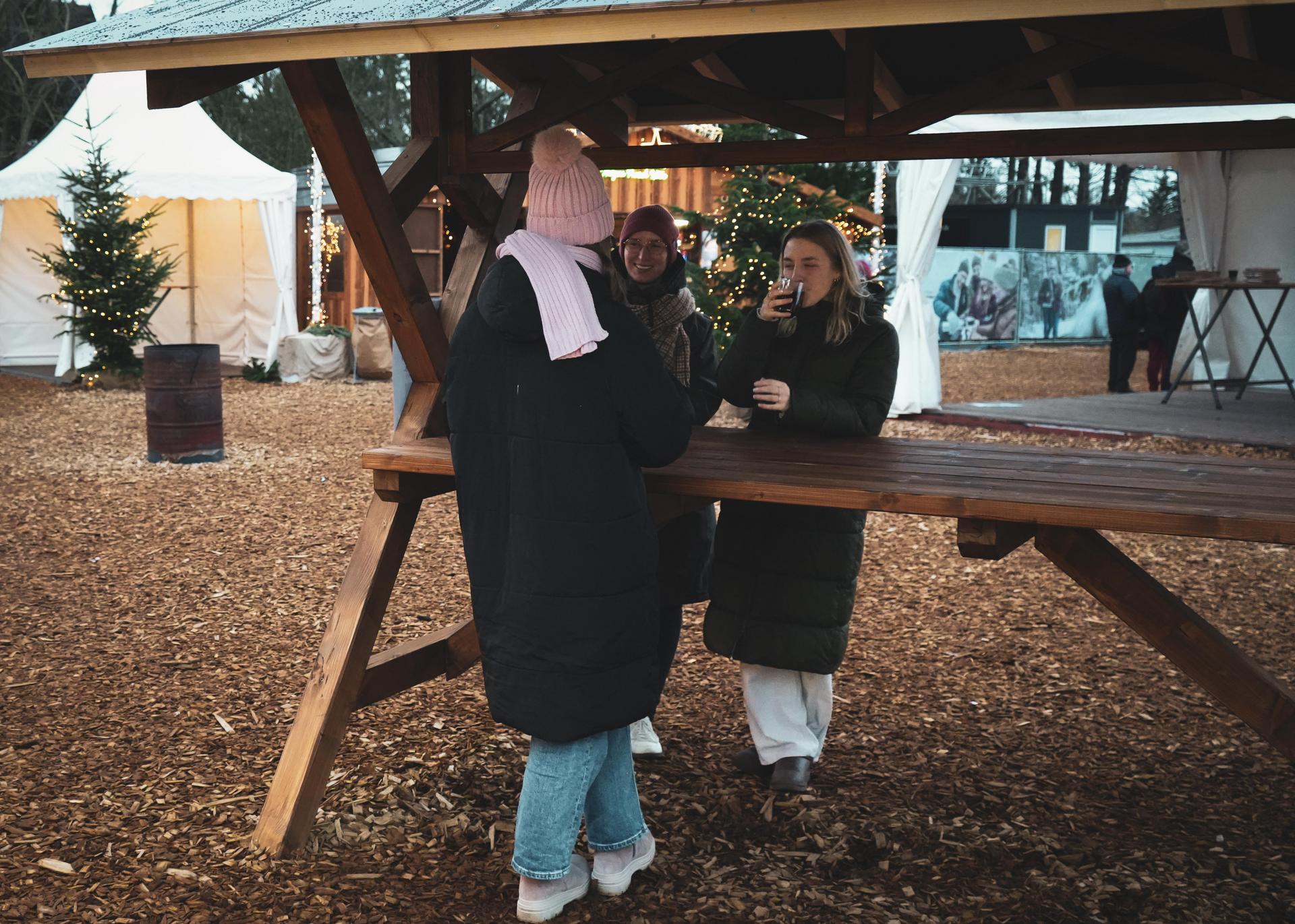Fröhliche Personen trinken Glühwein auf dem Weihnachtsmarkt